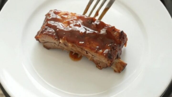 Slow-cooker BBQ ribs glistening with sticky sauce on a white plate.