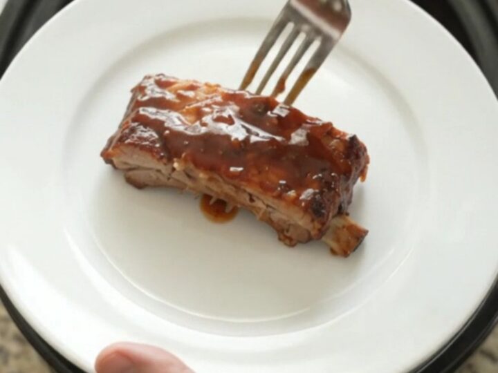 Slow-cooker BBQ ribs glistening with sticky sauce on a white plate.
