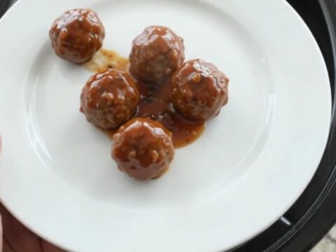 Glossy sweet and tangy cocktail meatballs in a slow cooker with a shiny mahogany glaze