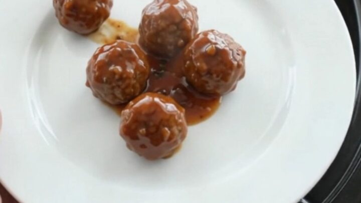 Glossy sweet and tangy cocktail meatballs in a slow cooker with a shiny mahogany glaze