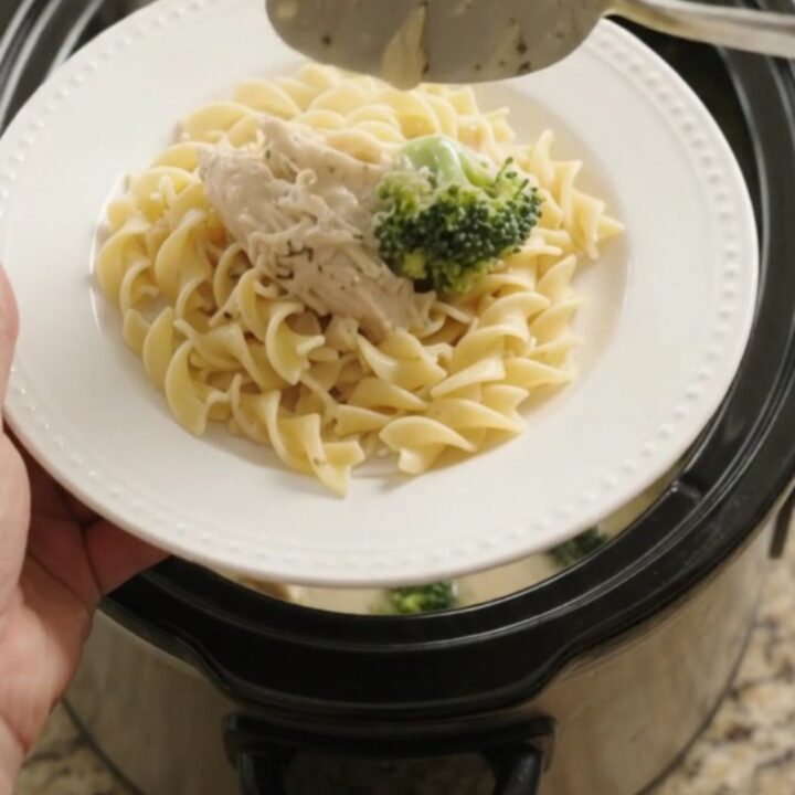 Slow cooker filled with creamy Parmesan broccoli chicken, ready to serve