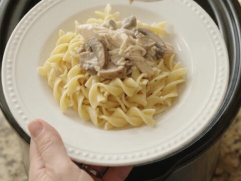 Creamy Parmesan mushroom chicken in a slow cooker with a spoon lifting a bite.