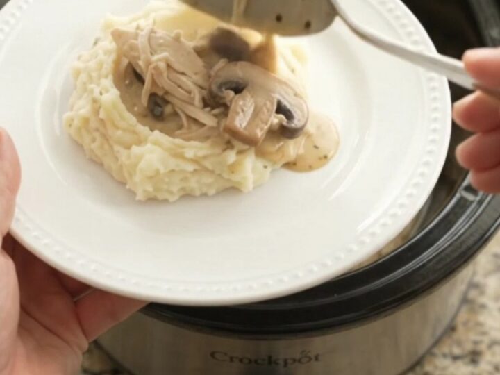 Creamy Swiss mushroom chicken in a slow cooker, topped with melted cheese and mushrooms.