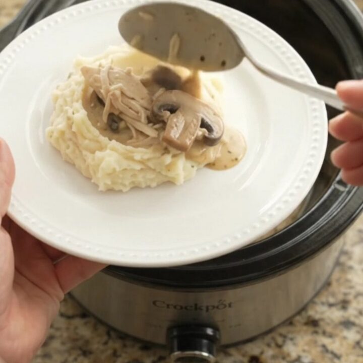 Creamy Swiss mushroom chicken in a slow cooker, topped with melted cheese and mushrooms.