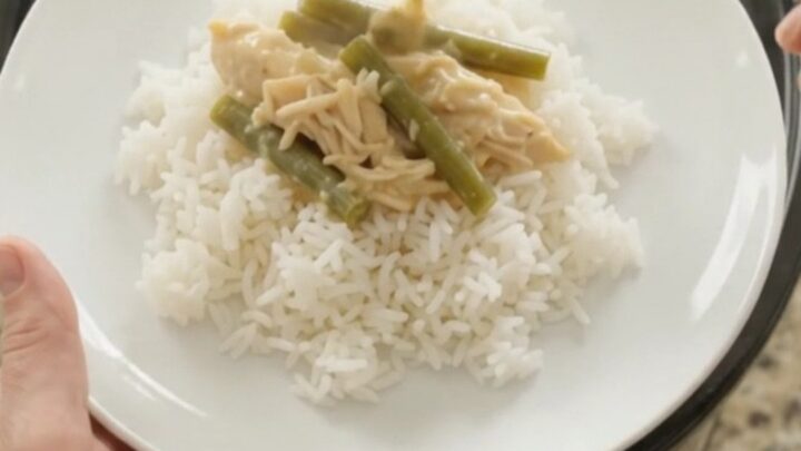 Slow cooker filled with creamy cheddar chicken and green beans, bubbling and golden