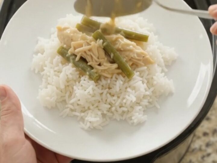 Slow cooker filled with creamy cheddar chicken and green beans, bubbling and golden