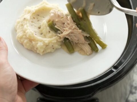 Creamy Swiss green bean chicken in a slow cooker, with melted cheese and tender chicken pieces