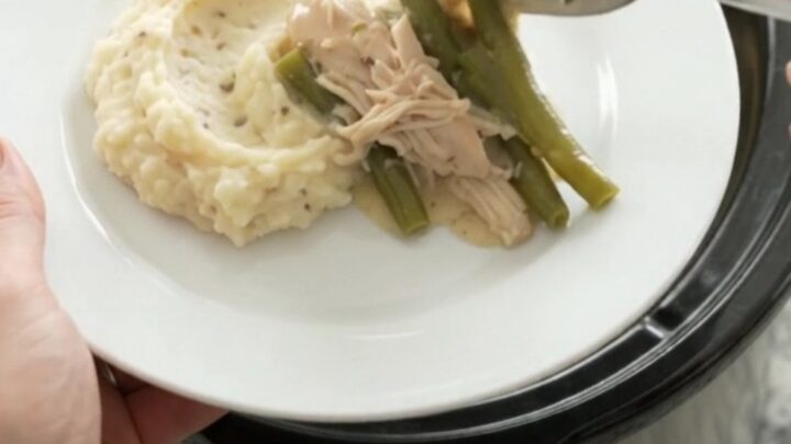 Creamy Swiss green bean chicken in a slow cooker, with melted cheese and tender chicken pieces