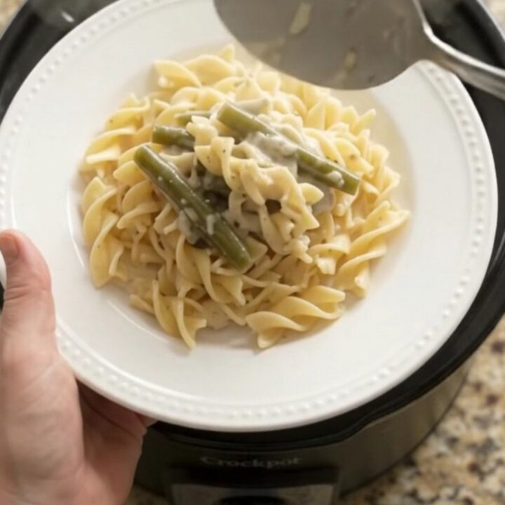 Creamy Parmesan green bean chicken in a slow cooker, with shredded chicken and green beans in a velvety sauce