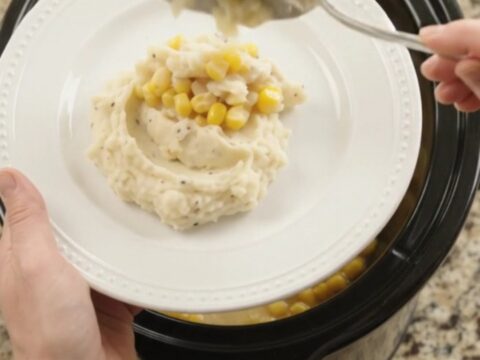 Creamy Swiss sweet corn chicken in a slow cooker with shredded chicken and melted cheese
