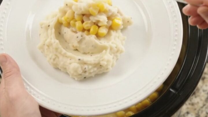 Creamy Swiss sweet corn chicken in a slow cooker with shredded chicken and melted cheese
