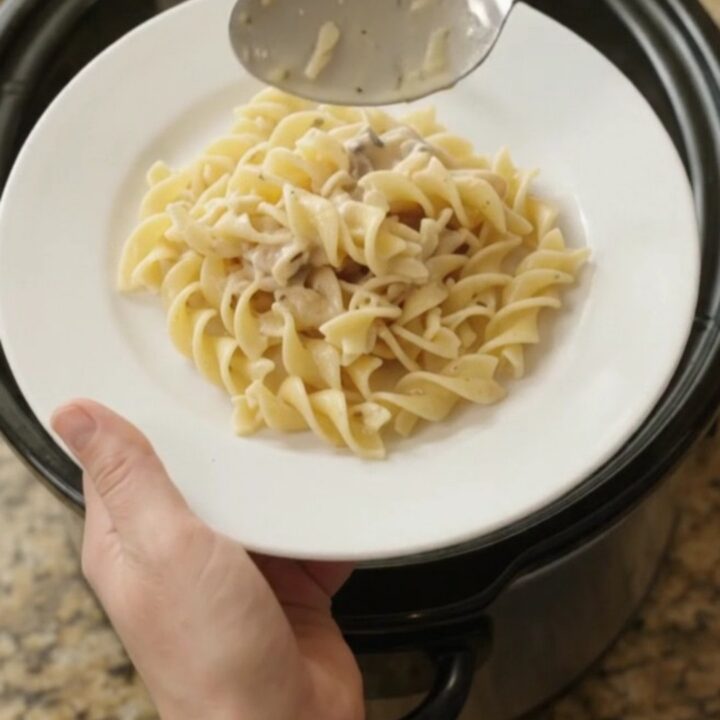 Creamy Parmesan chicken and baby potatoes in a slow cooker, topped with melted cheese and herbs.