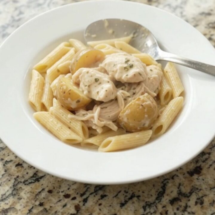 Creamy mozzarella chicken and baby potatoes in a slow cooker, topped with melted cheese and garlic butter.