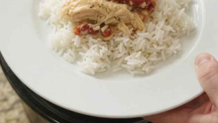 Creamy cheddar sun-dried tomato chicken in a slow cooker, bubbling with melted cheese and tomato ribbons.