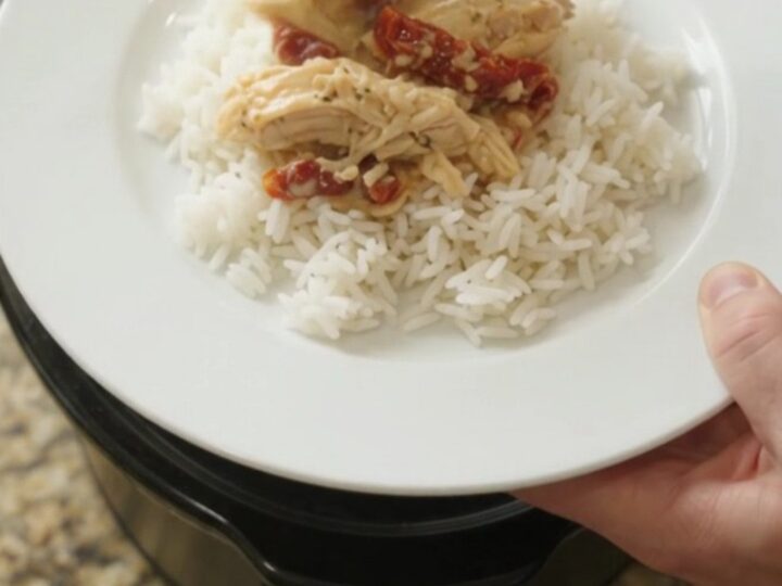 Creamy cheddar sun-dried tomato chicken in a slow cooker, bubbling with melted cheese and tomato ribbons.