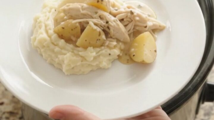 Creamy Swiss baby potato chicken in a slow cooker, topped with melted cheese and steam rising.