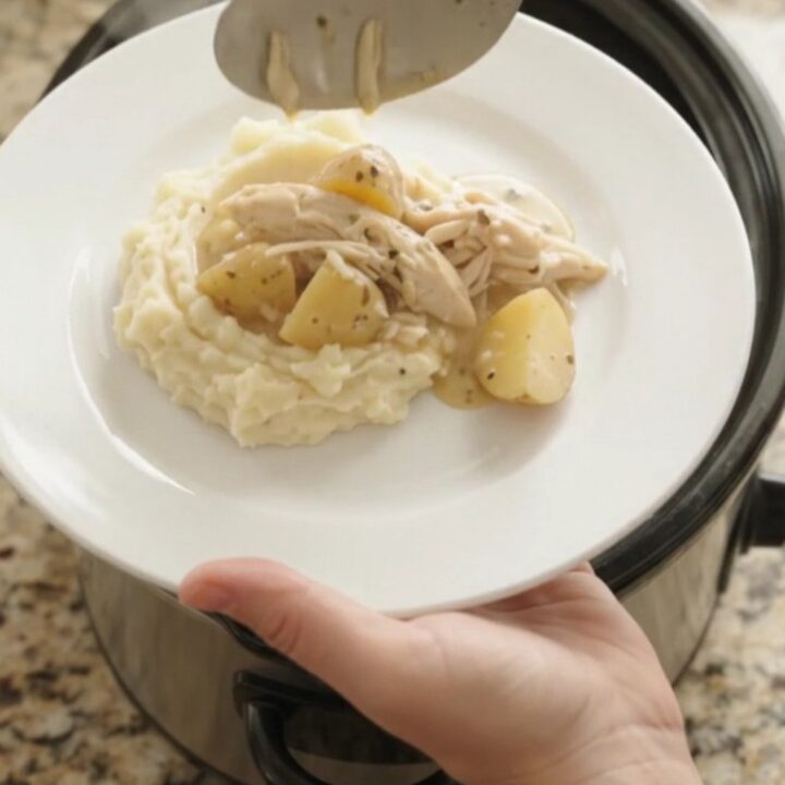 Creamy Swiss baby potato chicken in a slow cooker, topped with melted cheese and steam rising.
