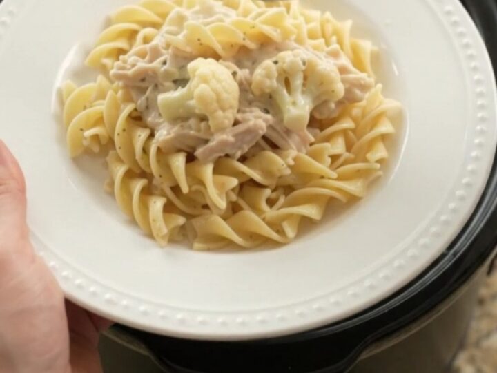 Creamy Parmesan cauliflower chicken in a slow cooker, with a spoon lifting a bite