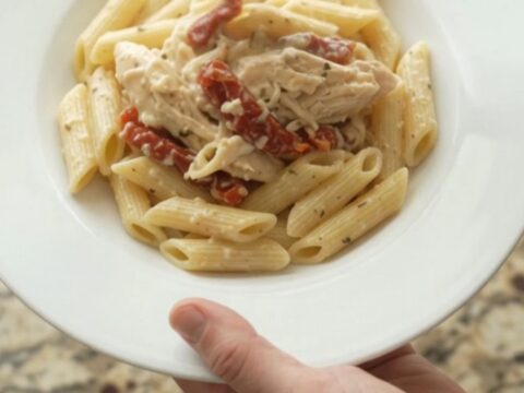 Creamy mozzarella sun-dried tomato chicken in a slow cooker, topped with melted cheese and herbs