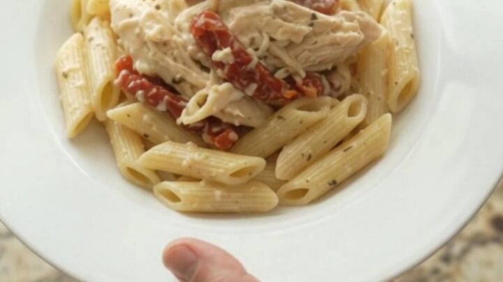 Creamy mozzarella sun-dried tomato chicken in a slow cooker, topped with melted cheese and herbs