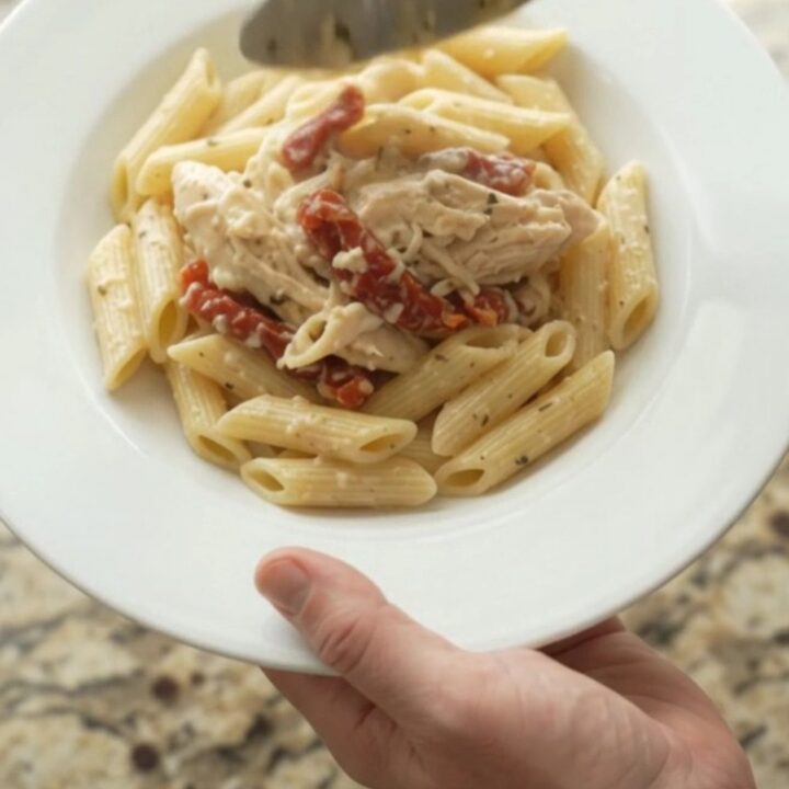 Creamy mozzarella sun-dried tomato chicken in a slow cooker, topped with melted cheese and herbs