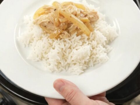 Creamy cheddar French onion chicken in a slow cooker, topped with melted cheese and caramelized onions