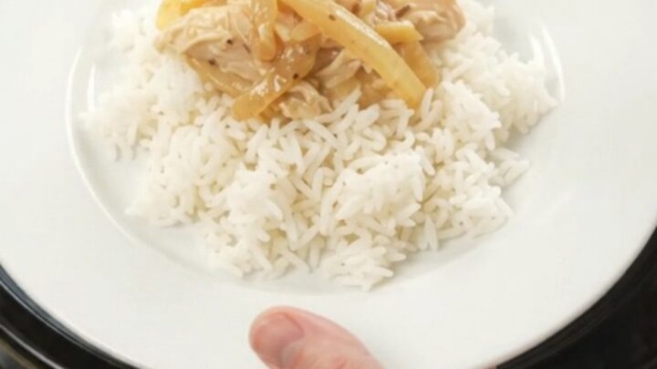 Creamy cheddar French onion chicken in a slow cooker, topped with melted cheese and caramelized onions
