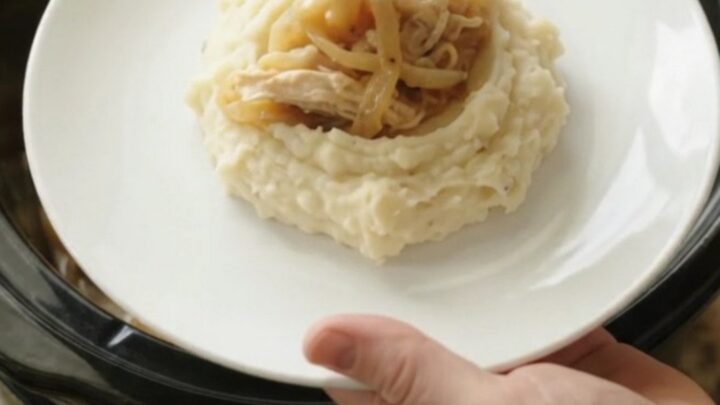 Creamy Swiss French Onion Chicken in a slow cooker, topped with melted cheese and onions