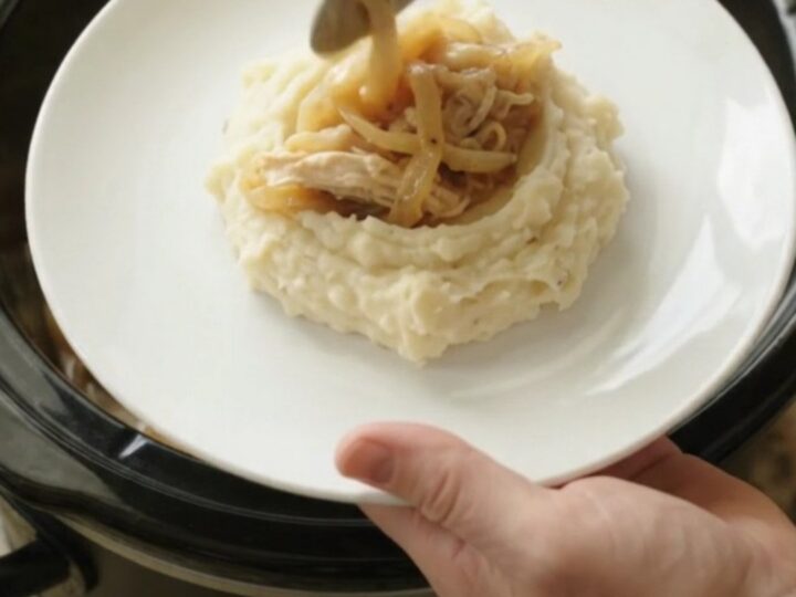Creamy Swiss French Onion Chicken in a slow cooker, topped with melted cheese and onions