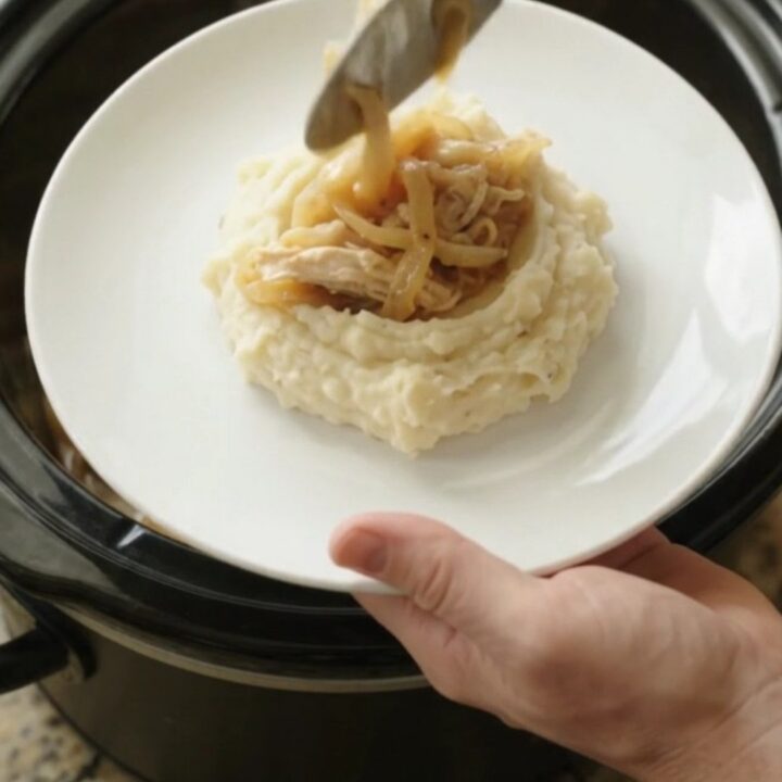Creamy Swiss French Onion Chicken in a slow cooker, topped with melted cheese and onions