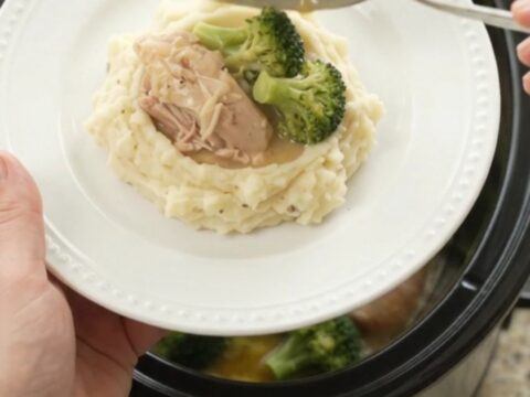 Slow cooker full of creamy Swiss broccoli chicken thighs, bubbling and glossy