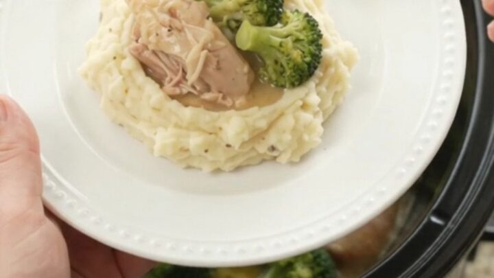 Slow cooker full of creamy Swiss broccoli chicken thighs, bubbling and glossy