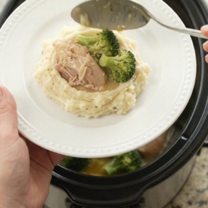 Slow cooker full of creamy Swiss broccoli chicken thighs, bubbling and glossy