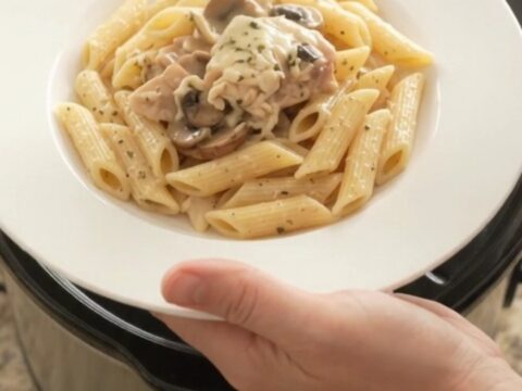 Slow cooker full of creamy mozzarella mushroom chicken thighs, bubbling and steaming.