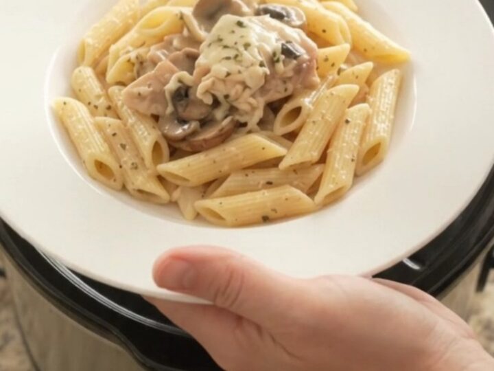 Slow cooker full of creamy mozzarella mushroom chicken thighs, bubbling and steaming.
