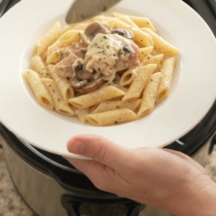 Slow cooker full of creamy mozzarella mushroom chicken thighs, bubbling and steaming.