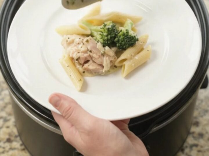 Slow cooker filled with creamy mozzarella broccoli chicken thighs, bubbling in a rich garlic sauce