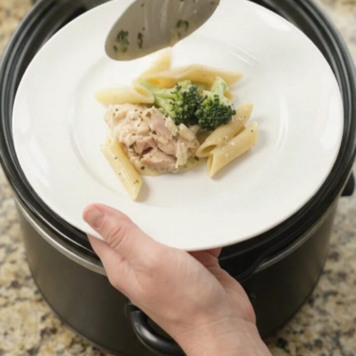 Slow cooker filled with creamy mozzarella broccoli chicken thighs, bubbling in a rich garlic sauce