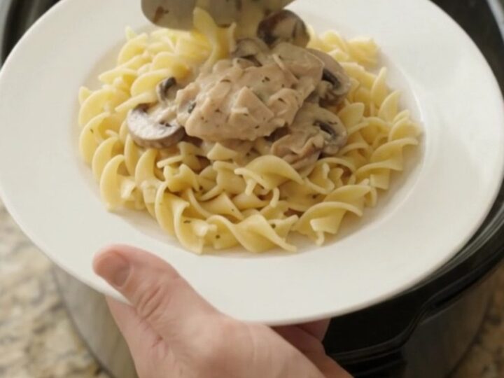 Creamy Parmesan mushroom chicken thighs in a slow cooker, with a velvety white gravy and mushrooms.