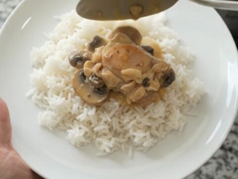 Slow cooker filled with creamy cheddar mushroom chicken thighs, topped with melted cheese and mushrooms.