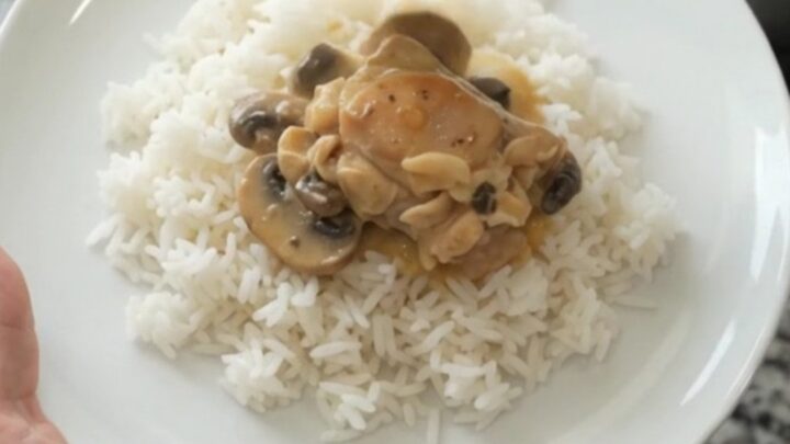Slow cooker filled with creamy cheddar mushroom chicken thighs, topped with melted cheese and mushrooms.