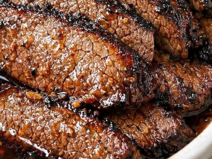 Extreme close-up of glossy garlic butter jus drizzled over tender, seared beef brisket slices.