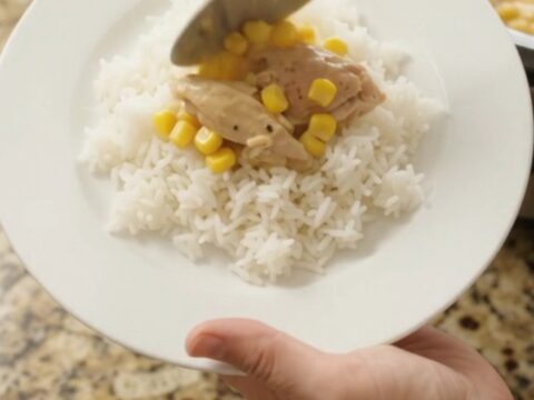 Creamy cheddar corn chicken thighs bubbling in a slow cooker, with melted cheese and golden corn visible.