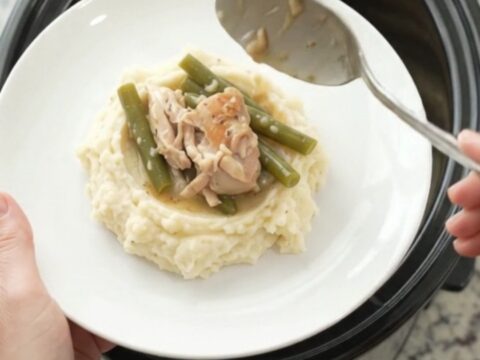 Slow cooker filled with chicken thighs and green beans in creamy Swiss sauce