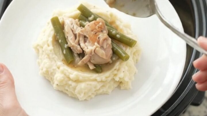 Slow cooker filled with chicken thighs and green beans in creamy Swiss sauce