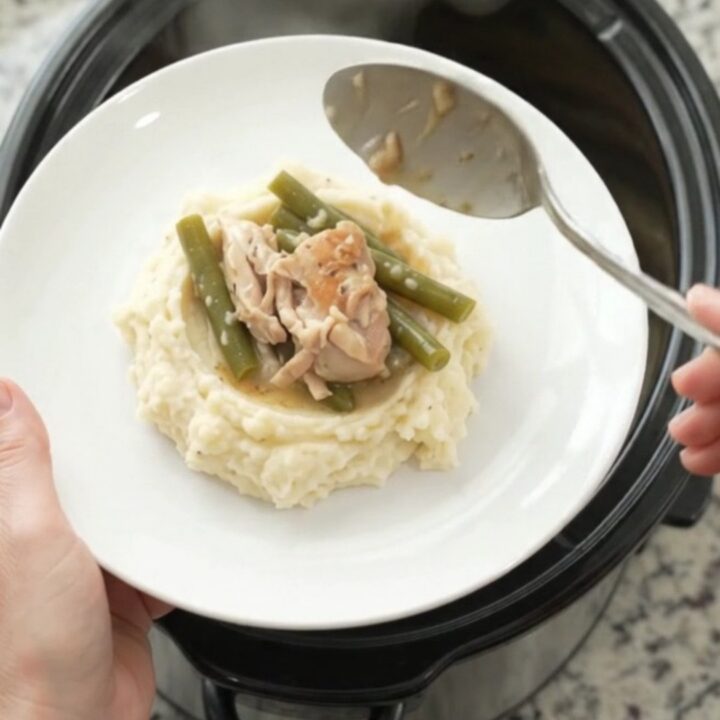 Slow cooker filled with chicken thighs and green beans in creamy Swiss sauce