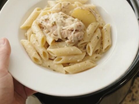 Slow cooker full of creamy mozzarella chicken thighs and baby potatoes with a rich, bubbling sauce