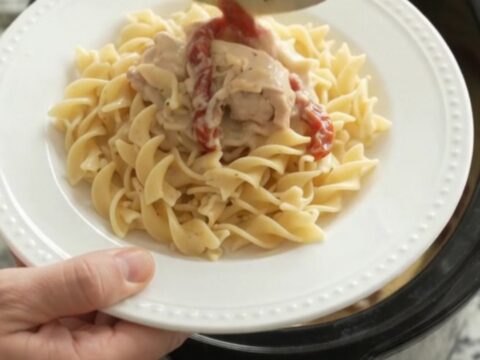 Creamy slow cooker chicken thighs with sun-dried tomatoes and Parmesan sauce, served over buttered noodles