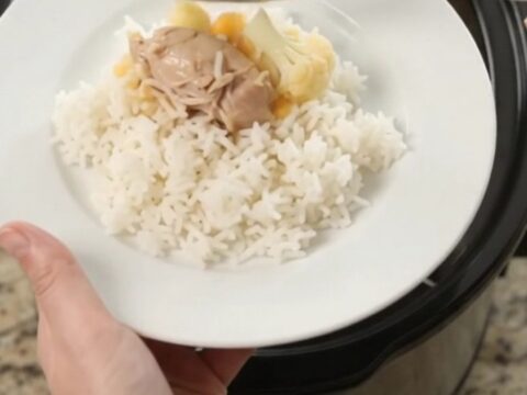 Slow cooker filled with creamy cheddar chicken and cauliflower, with a spoon lifting a saucy bite