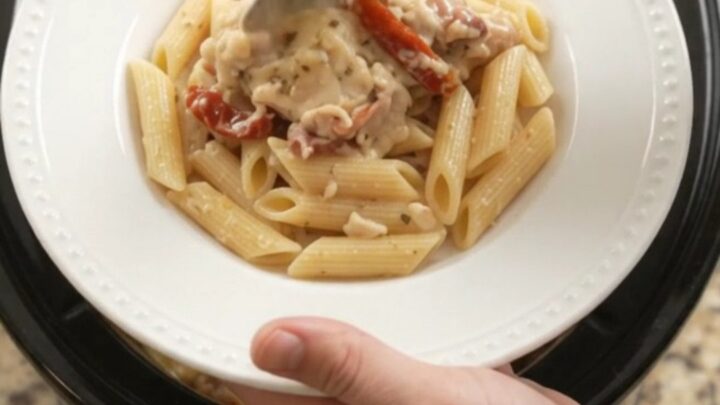 Slow cooker full of creamy mozzarella sun-dried tomato chicken thighs, bubbling with cheese and herbs